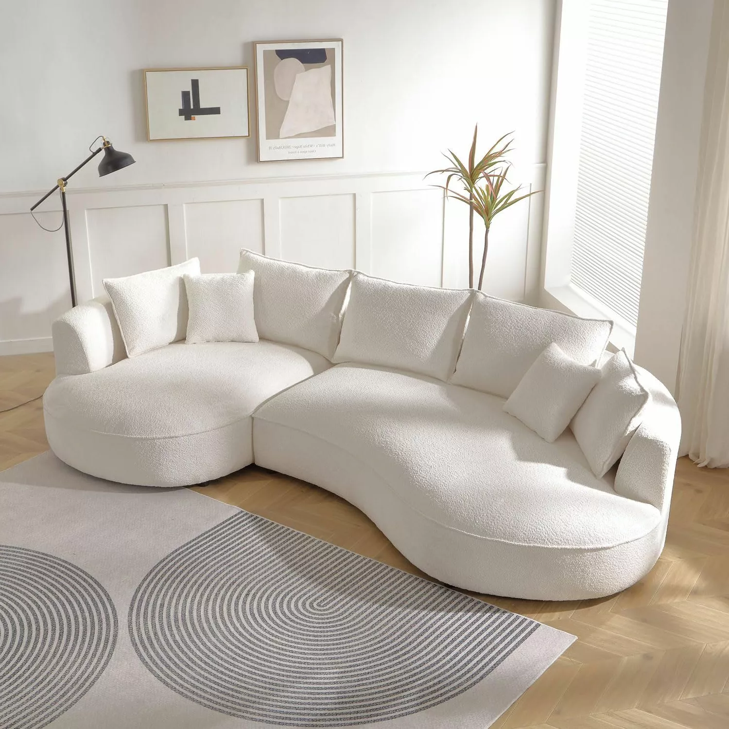 Embrace light and simplicity in a minimalist living room featuring a chic curved sofa and clean design elements.