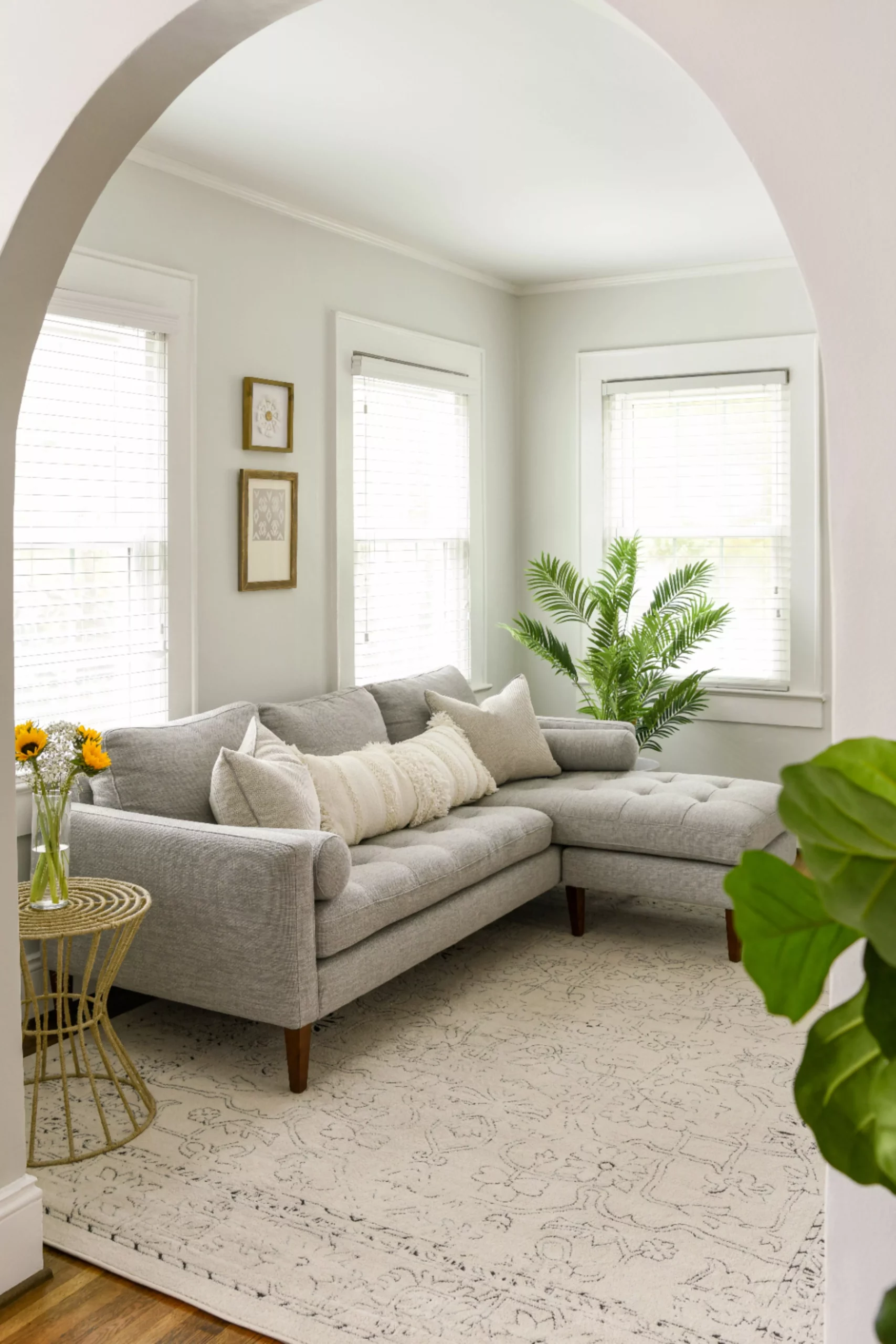 Discover the tranquil charm of this light-filled living room, featuring a plush sectional, elegant décor, and serene design elements.