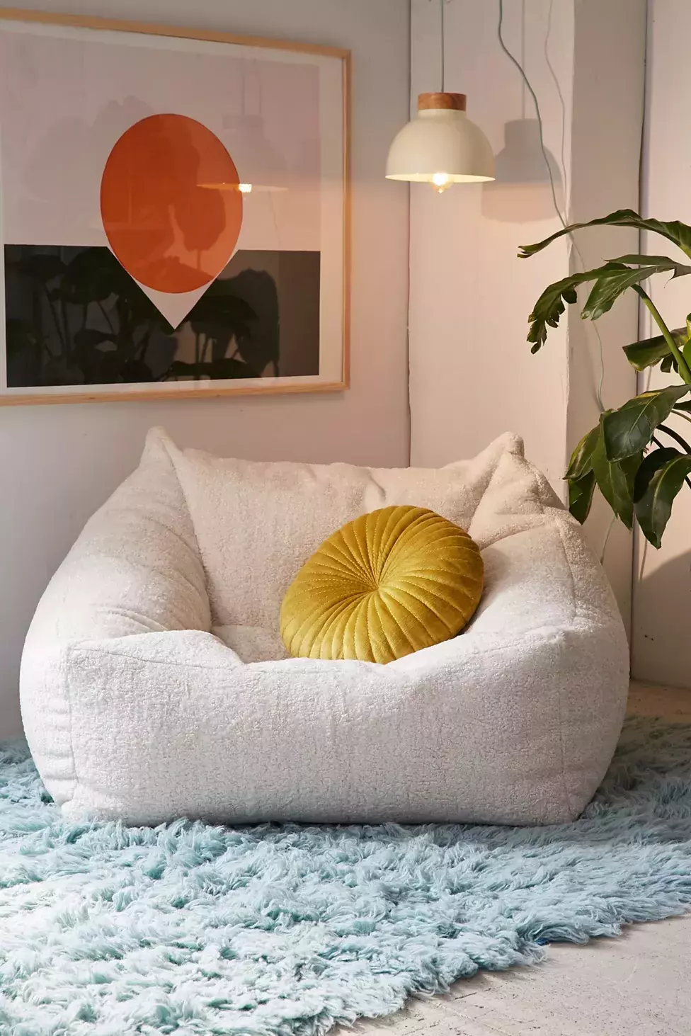 Experience ultimate comfort in this plush white chair, accented with a mustard pillow and modern abstract art.