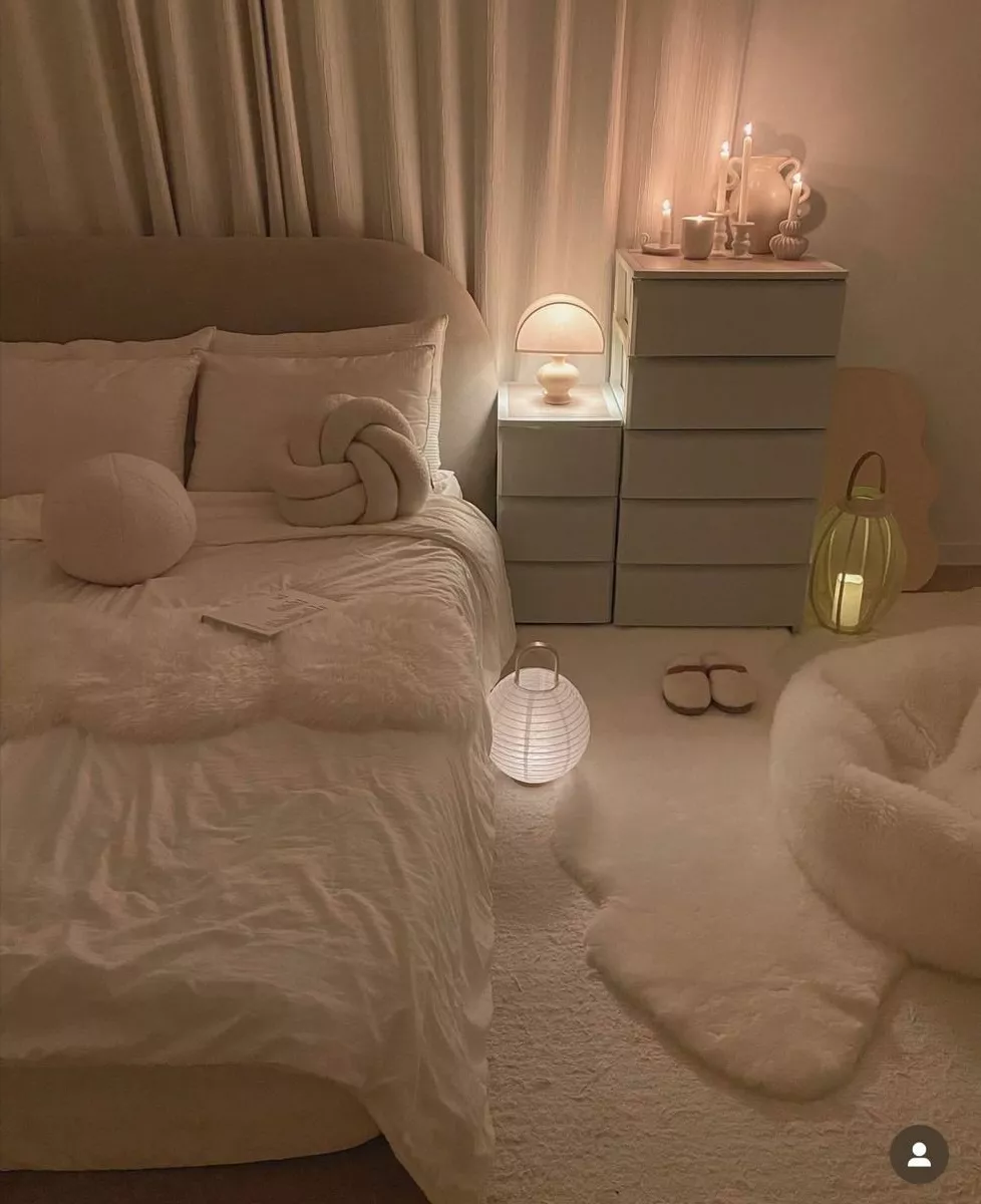 Discover a tranquil bedroom setup with soft whites and warm lighting that creates an inviting and peaceful atmosphere.