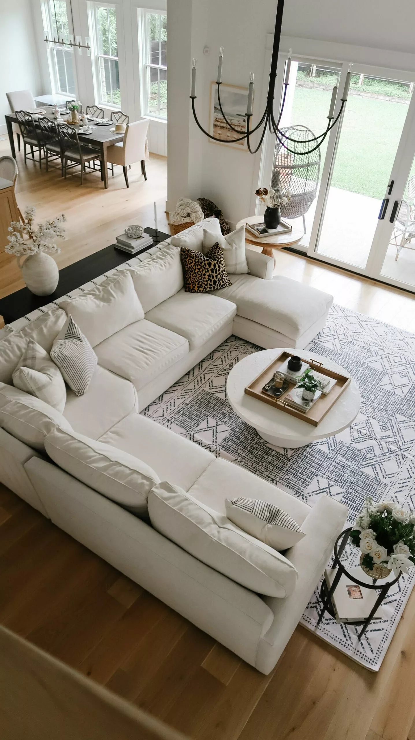 Transform your space with this elegantly arranged living room featuring a plush sectional, chic decor, and a refined dining area.