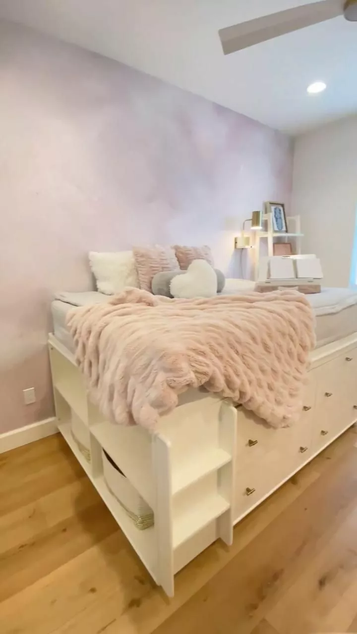 Discover a chic sanctuary with a storage-integrated bed, blush pink accents, and plush decor for the ultimate cozy vibe.