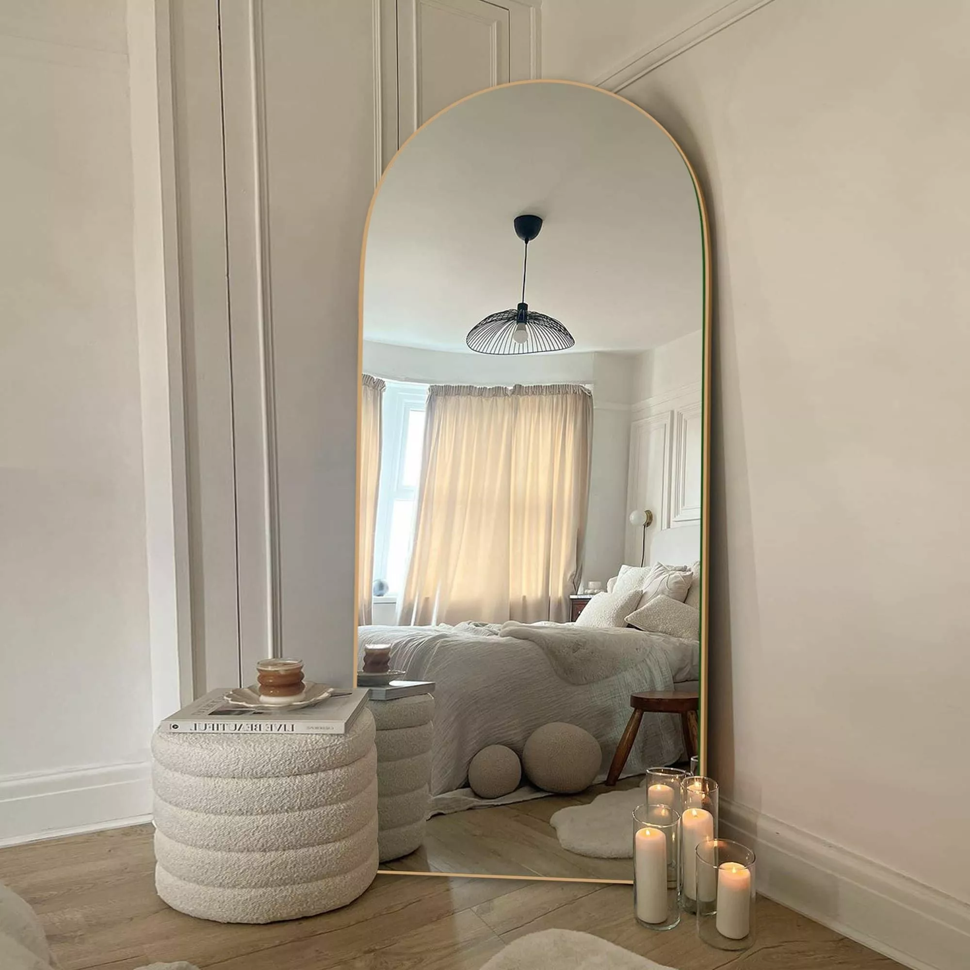 Step into a serene ambiance with this minimalist bedroom adorned with a striking arched mirror that adds depth and elegance.