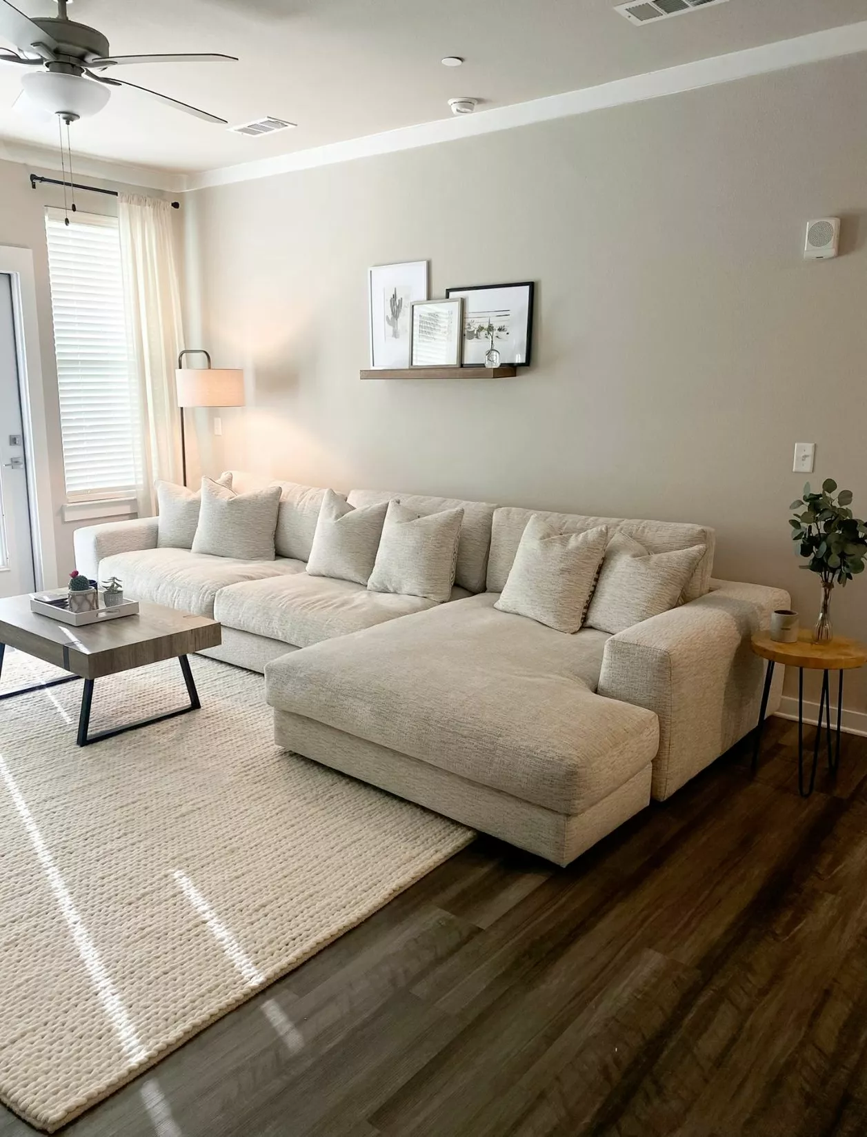 Dive into the serene ambiance of this neutral-toned living room featuring a plush sectional, tasteful decor, and natural light. Discover perfect comfort!