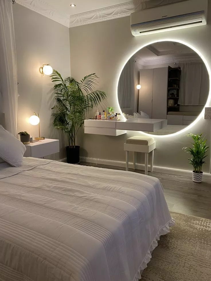 Discover the charm of an elegantly minimalist bedroom featuring a captivating illuminated circular mirror that adds a touch of modern luxury.