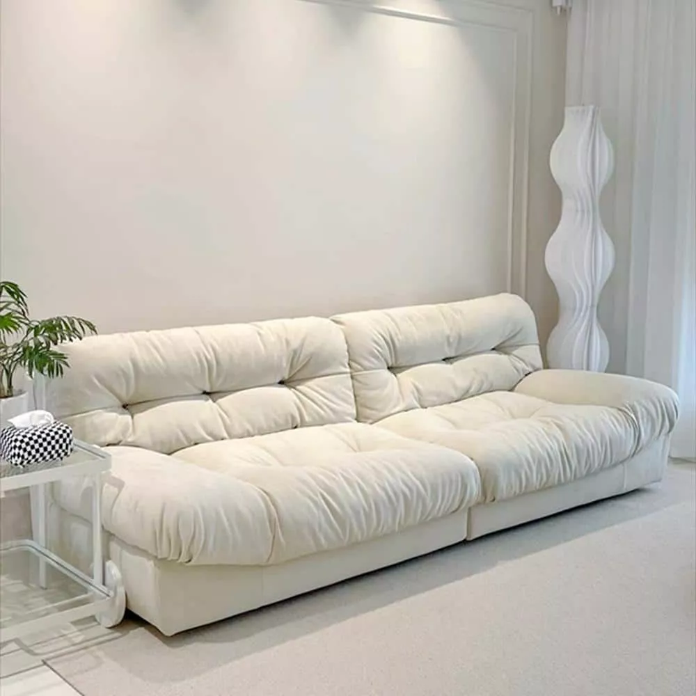 A serene living room featuring a plush, cloud-like white sofa complemented by modern decor elements in a minimalist setting.