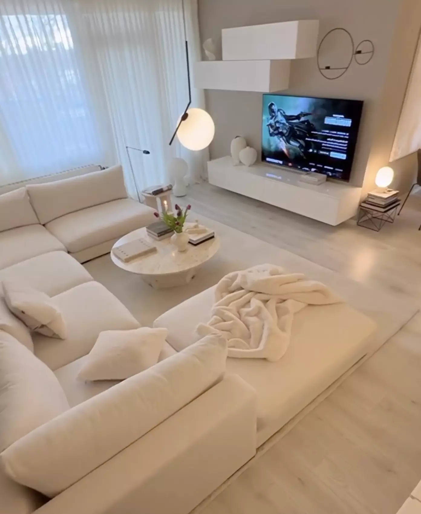 Explore this modern living room featuring plush white furnishings, chic minimal decor, and a serene ambiance perfect for cozy evenings and stylish gatherings.