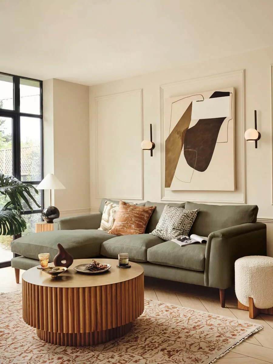 Embrace the perfect blend of comfort and contemporary style in this chic living room oasis, featuring a lush olive-green sofa, artistic décor, and warm lighting.