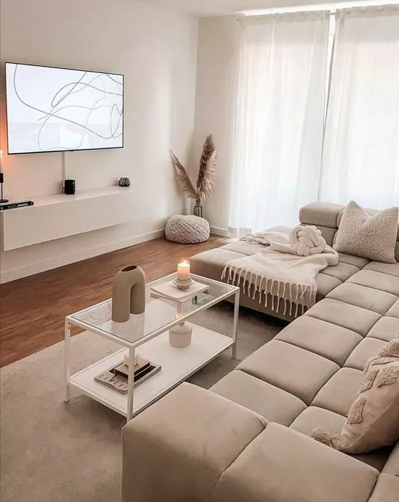 This serene living room features minimalist decor with beige tones, comfy seating, modern art, and cozy accents, creating a perfect harmony of style and comfort.